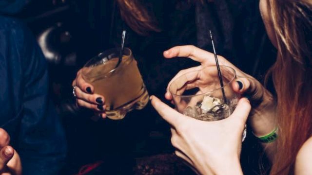People are enjoying drinks and laughing in a social setting.
