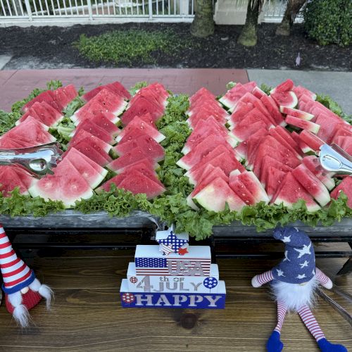 Slices of watermelon arranged on lettuce, surrounded by Fourth of July-themed decorations and utensils on a table.