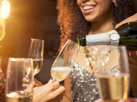People toasting champagne glasses at a celebration, smiles, warm lighting, festive party vibe.