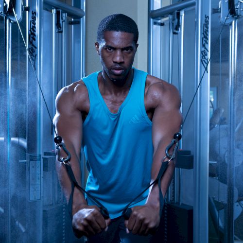 A person in a blue tank top is using a cable machine in a gym setting, surrounded by a misty ambiance.
