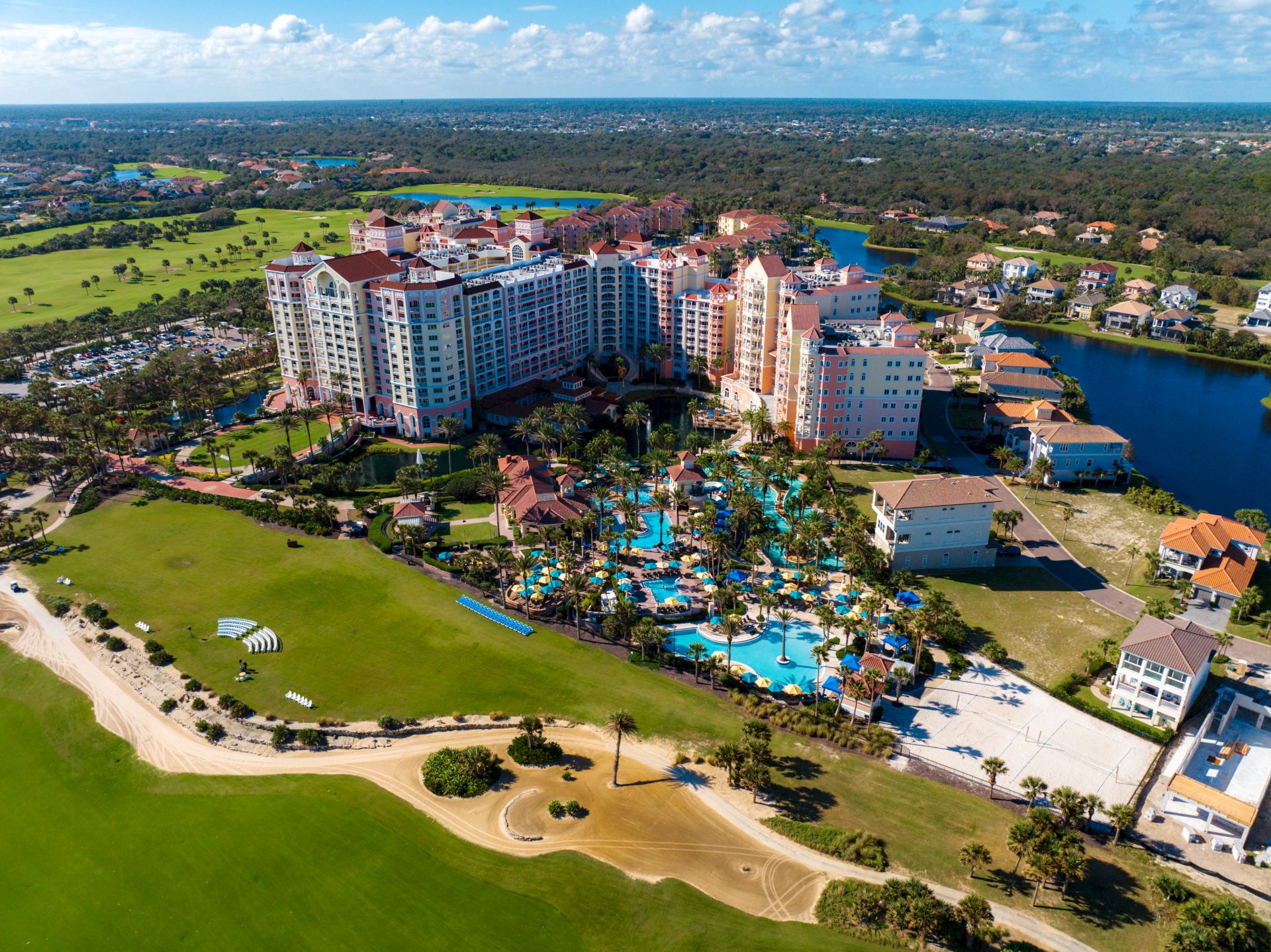The image shows a large resort complex with multiple buildings, surrounded by pools, greenery, and a golf course.