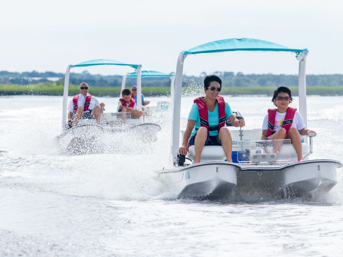 People are riding small motorized boats on the water, wearing life jackets.