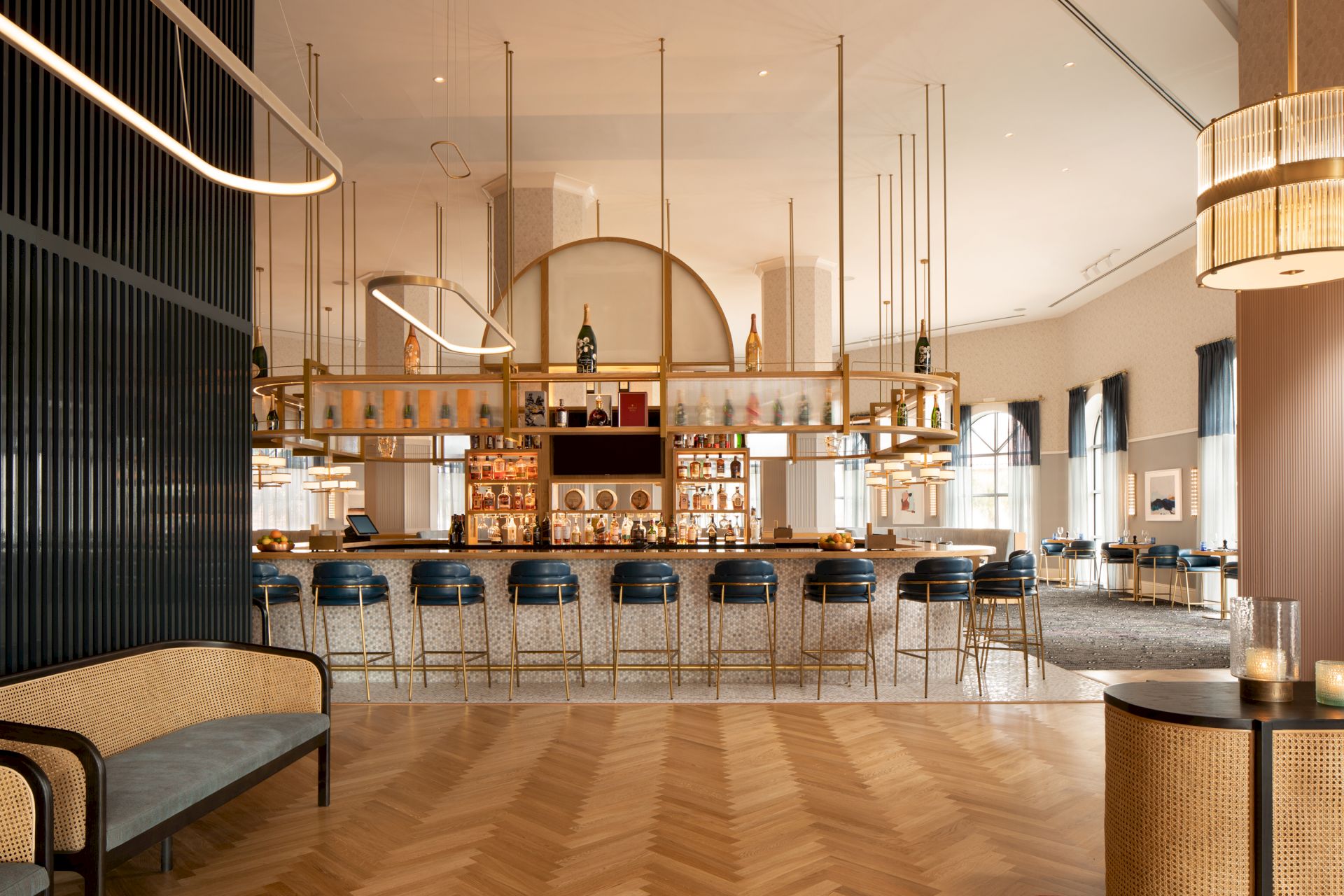 The image shows a stylish bar interior with modern design, featuring a long counter, high chairs, and elegant lighting.