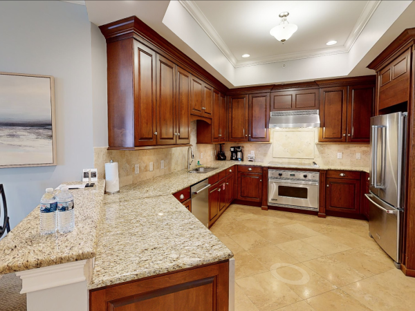 A modern kitchen with wooden cabinets, stainless steel appliances, granite countertops, and a neutral color scheme on the walls and floor.
