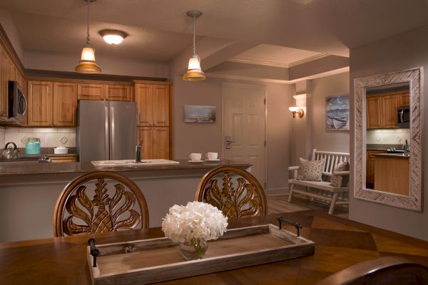 A stylish kitchen and dining area with wooden cabinets, pendant lights, and a table featuring a centerpiece of white flowers ends the sentence.