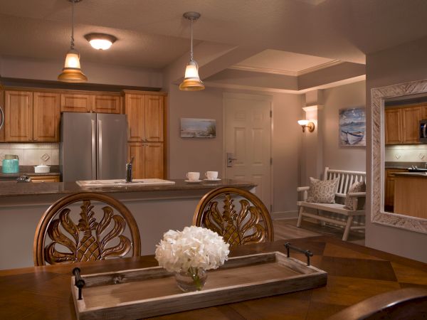 A stylish kitchen and dining area with wooden cabinets, pendant lights, and a table featuring a centerpiece of white flowers ends the sentence.