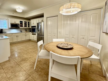 A modern kitchen and dining area with a round wooden table and white chairs, stainless appliances, and plenty of cabinet space.
