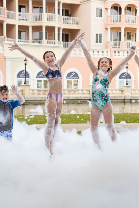 Top it off with a splashy dance moment as kids jump through bubbly foam near a resort pool, summer fun in the sun.