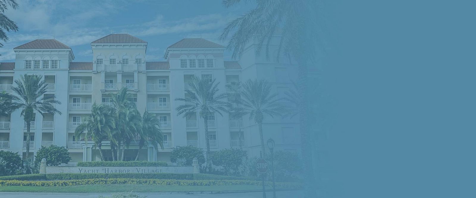 A multi-story building with palm trees in front and a blue overlay on the right side of the image.