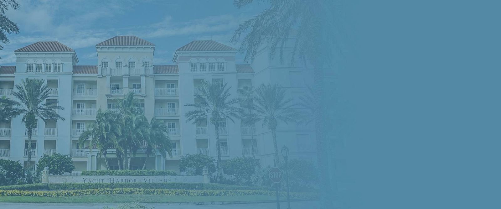 A large hotel or resort building with palm trees in front, bathed in a blue overlay, suggesting a sunny coastal retreat.