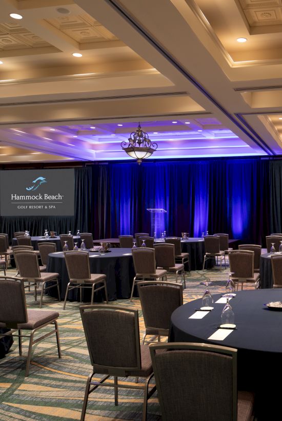 The image shows a conference room with tables, chairs, and screens displaying "Hammock Beach Golf Resort & Spa."
