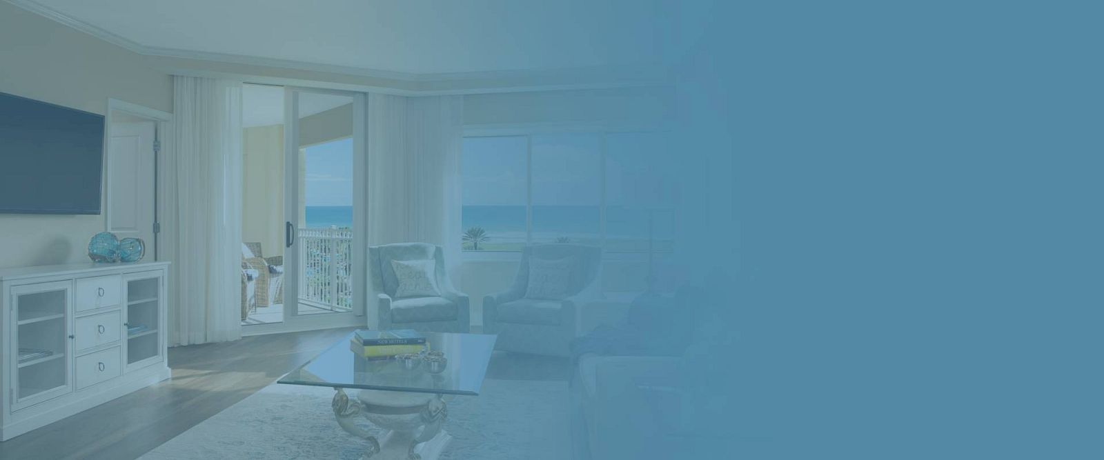 A bright living room with ocean view, glass doors, modern furniture, TV, and decor, partially obscured by blue overlay.