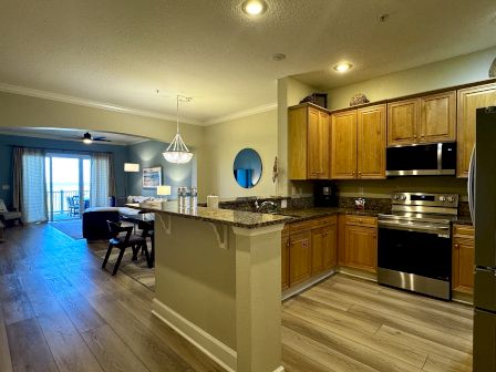Cozy open-concept kitchen and dining area with wooden cabinets, stainless steel appliances, a breakfast bar, and a view into the living room.