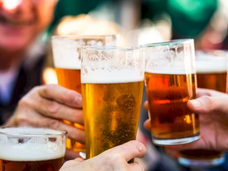 Friends clink frothy beer mugs&mdash;golden lager and amber ale, refreshing and celebratory.