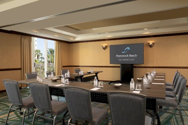 A conference room at Hammock Beach Resort, set up with chairs, tables, bottled water, notepads, and a presentation screen.