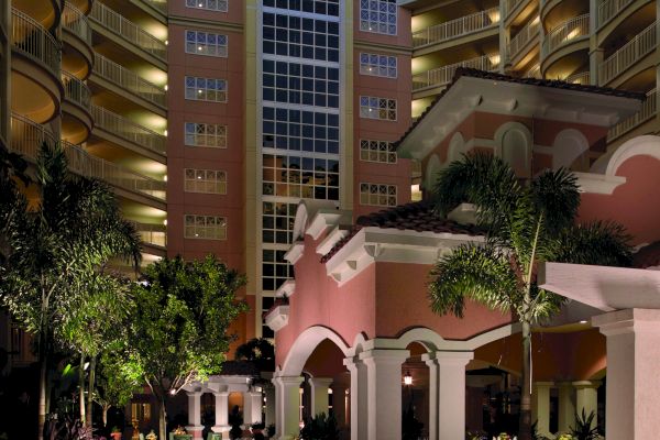 Outdoor courtyard of a hotel with tables, chairs, plants, and candles, surrounded by a multi-story building at dusk.