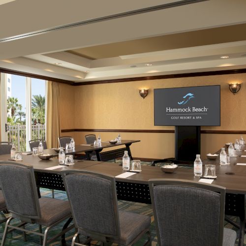 A conference room with chairs, tables, bottled water, and a screen displaying "Hammock Beach Golf Resort & Spa."