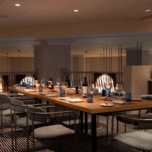 A stylish dining area with a long table set for a meal. Various wine bottles and glasses are arranged on the table and sideboard.