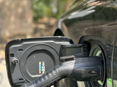 An electric vehicle is being charged with a charging cable connected to its charging port.