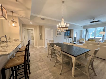 This image shows a modern open-plan living space with a kitchen, dining table, and cozy seating area.