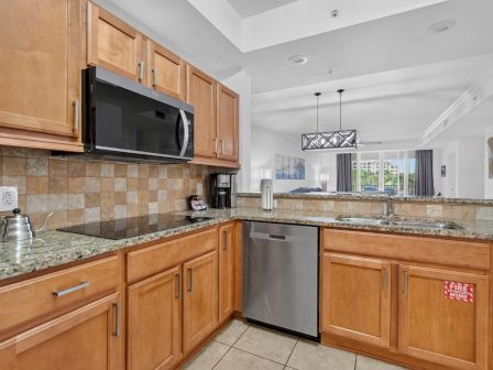 A bright kitchen with wooden cabinets, granite countertops, a microwave, coffee maker, and stainless dishwasher in a clean dining area.