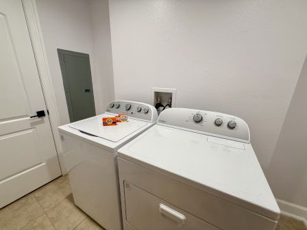 A laundry room with a washer, dryer, detergent, fabric softener sheets, and a wall cabinet.