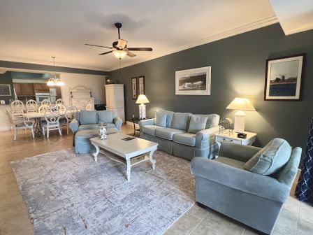 A cozy living and dining area with soft blue furniture, a textured rug, wall art, and warm lighting. Classic and inviting style.