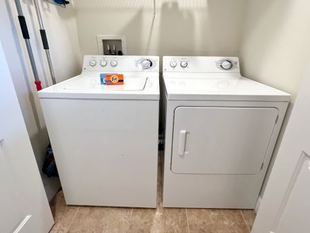 A laundry room with a washer, dryer, and a box of Tide detergent on the washer.