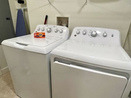 A laundry room with a washing machine and dryer, and a box of Tide detergent on top of the washer.