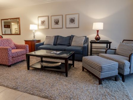 A cozy living room with a blue sofa, red patterned armchair, coffee table, and framed art on the wall, ending the sentence.