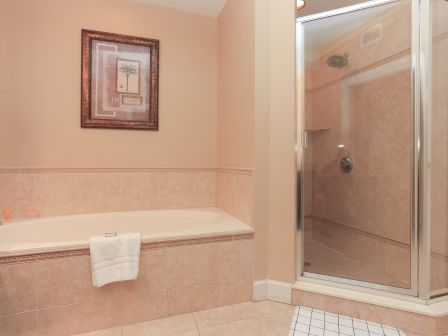 A bathroom with a bathtub, a glass-enclosed shower, and a framed picture on the wall.