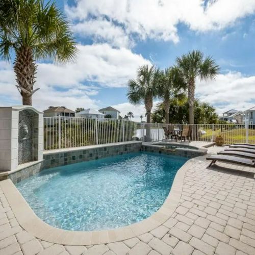 The image shows a backyard with a swimming pool, palm trees, lounge chairs, and a clear sky, creating a relaxing outdoor setting.