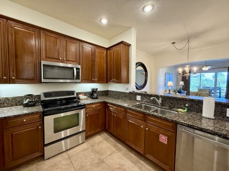 A modern kitchen with wooden cabinets, stainless steel appliances, a double sink, and a granite countertop.